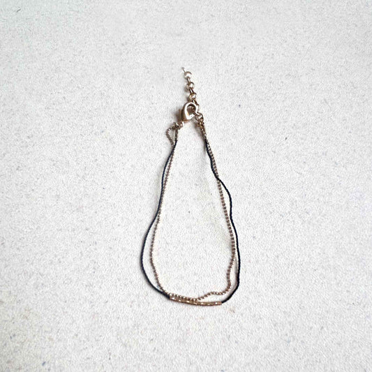 Pulsera hilito negro centro tubo dorado